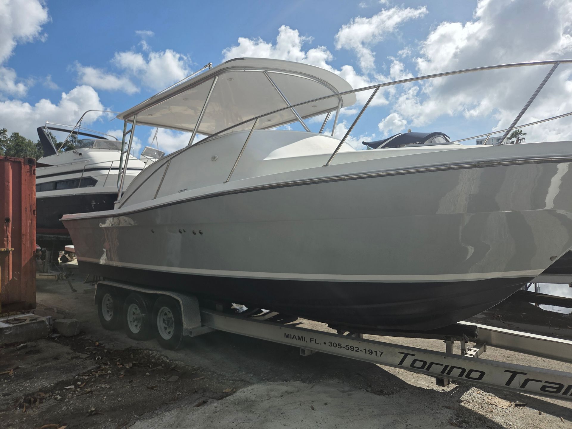 Gray boat on trailer under a cloudy sky.