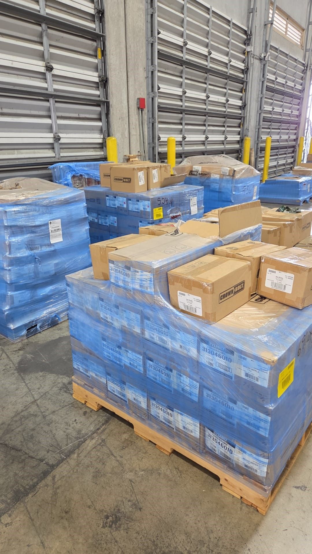 Pallets of packaged goods in a warehouse, wrapped in blue plastic.