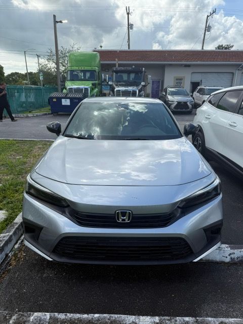 Silver Honda Civic parked in front of a building with trucks in the background.
