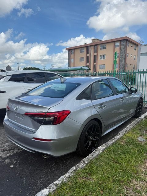 Silver Honda Civic parked next to a curb in front of a building with blue sky.