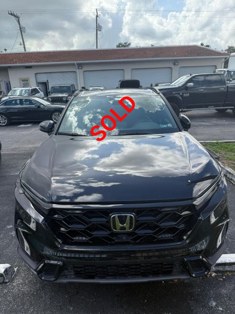 Dark gray Honda SUV parked in front of a building with a reflection of clouds on the windshield.