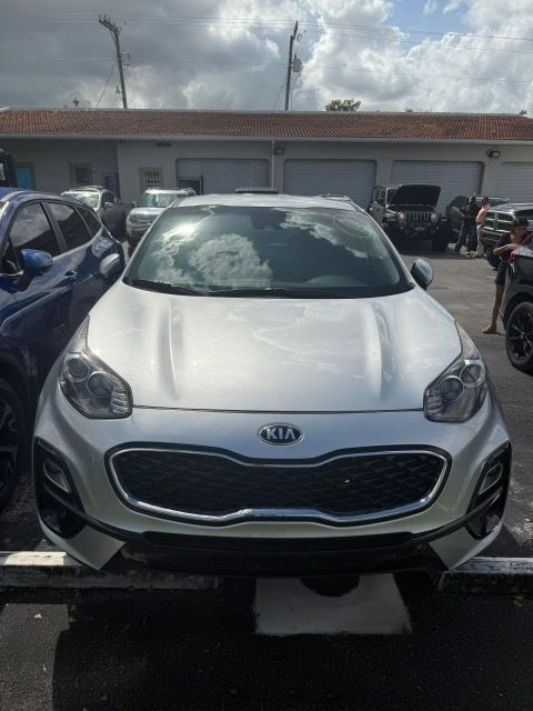 Silver Kia Sportage parked outside, with a dark grille and headlights.