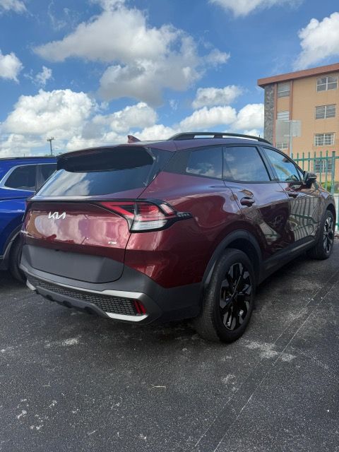 Red Kia Sportage SUV parked outdoors under a cloudy sky.