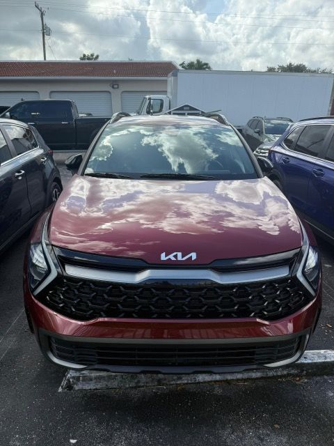 Red Kia SUV parked outside, front view.