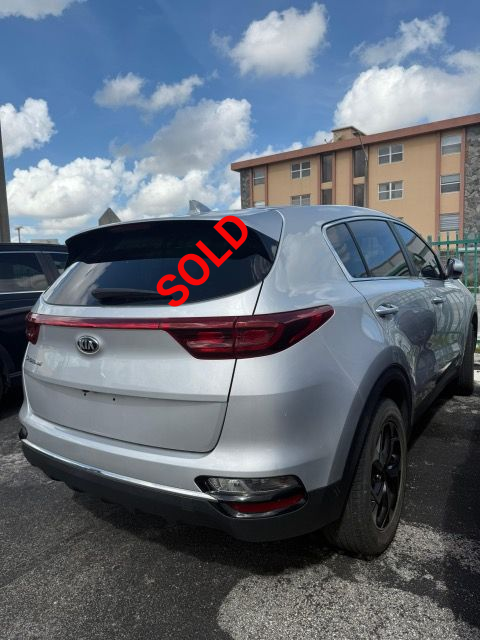 Silver Kia Sportage SUV parked in a parking lot on a sunny day.