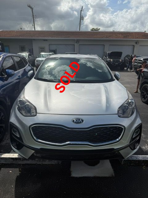 Silver Kia Sportage parked outside, with a dark grille and headlights.