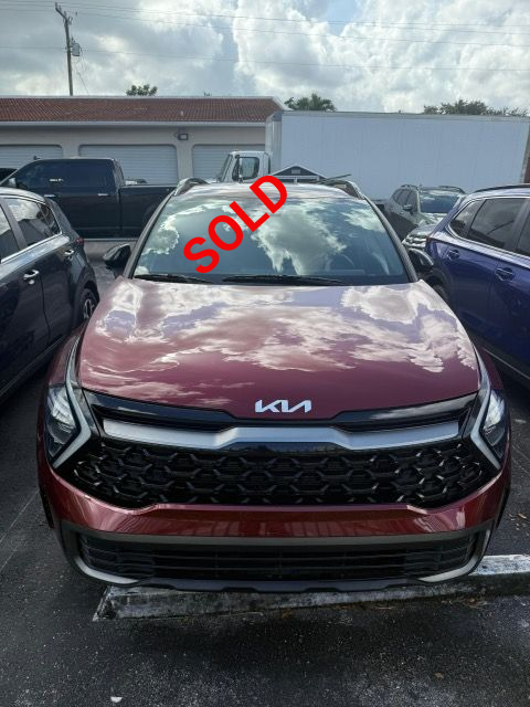 Red Kia SUV parked outside, front view.