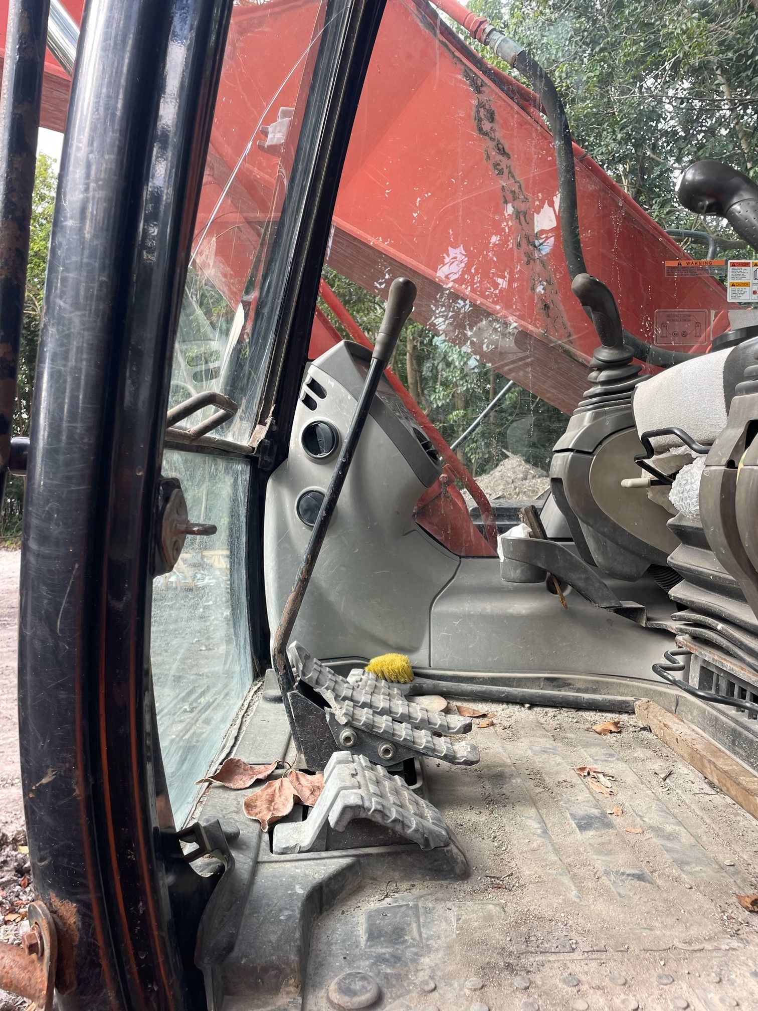 Inside of an excavator cab: levers, controls, and dirty floor.
