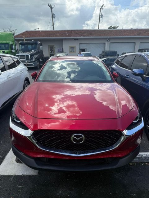 Red Mazda CX-30, front view, parked outside a building, reflection of sky on windshield.