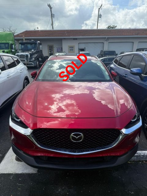 Red Mazda CX-30, front view, parked outside a building, reflection of sky on windshield.