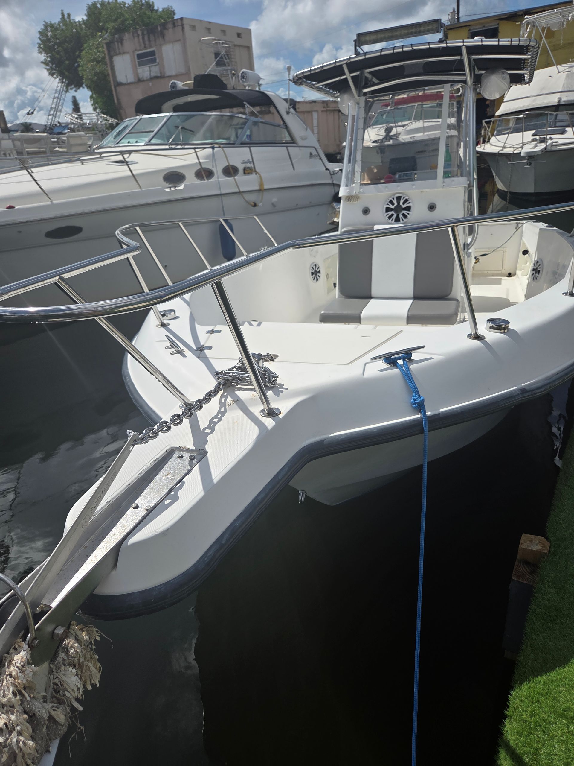 White center console boat docked with a blue rope, in a marina setting.