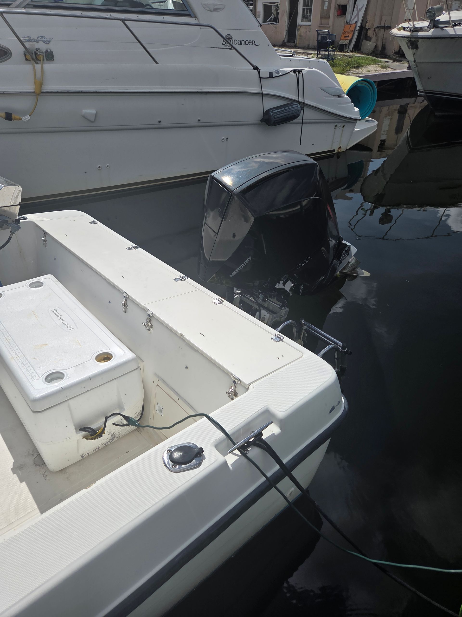 White motorboat in water next to larger white boat; black motor.