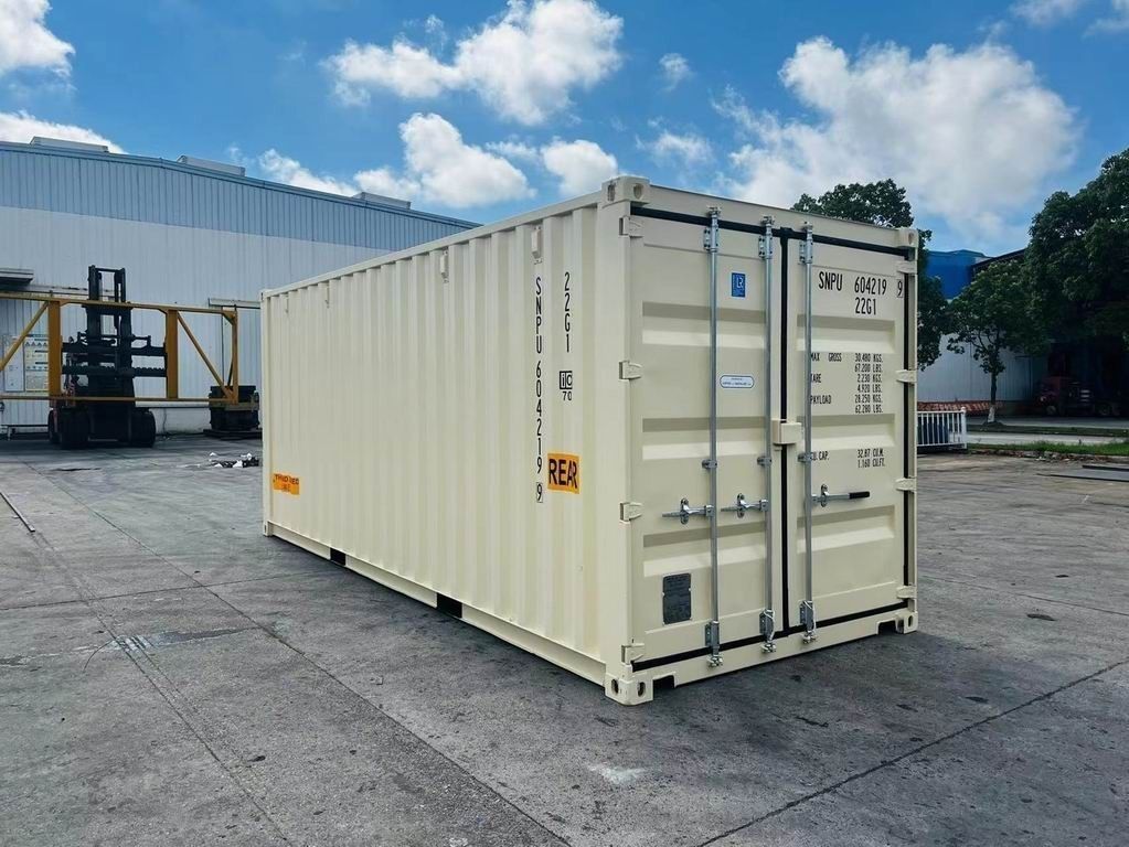 Beige shipping container on a concrete surface with a building and blue sky in the background.