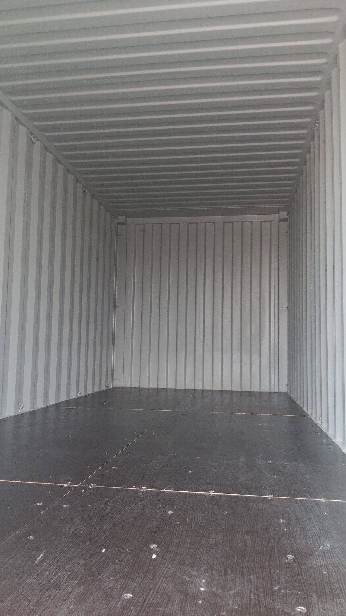 Empty gray shipping container interior with a dark floor.