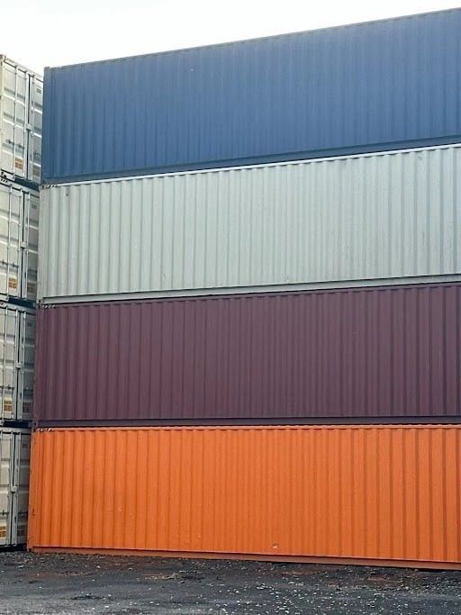Stacked colorful shipping containers: blue, beige, maroon, and orange.