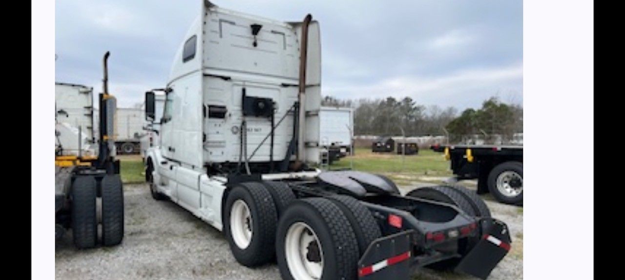 Rear view of a white semi-truck parked outside on a cloudy day.