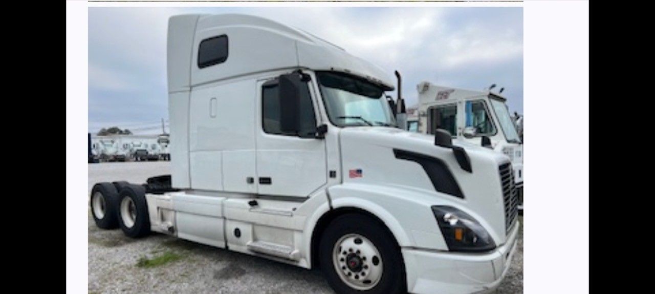 White Volvo semi-truck parked in an outdoor setting with overcast sky.