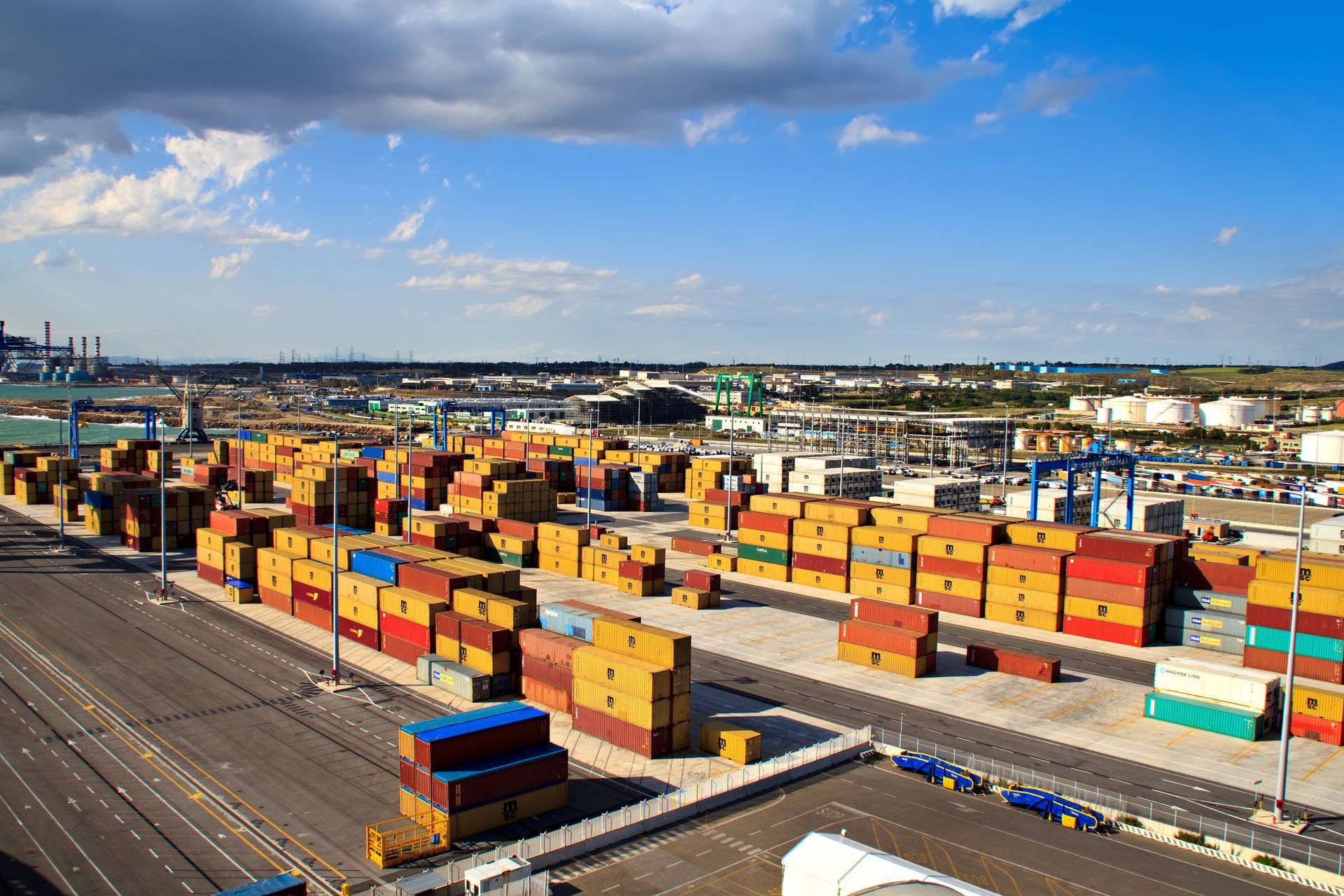 Shipping containers stacked in a harbor under a blue sky, illustrating global trade.