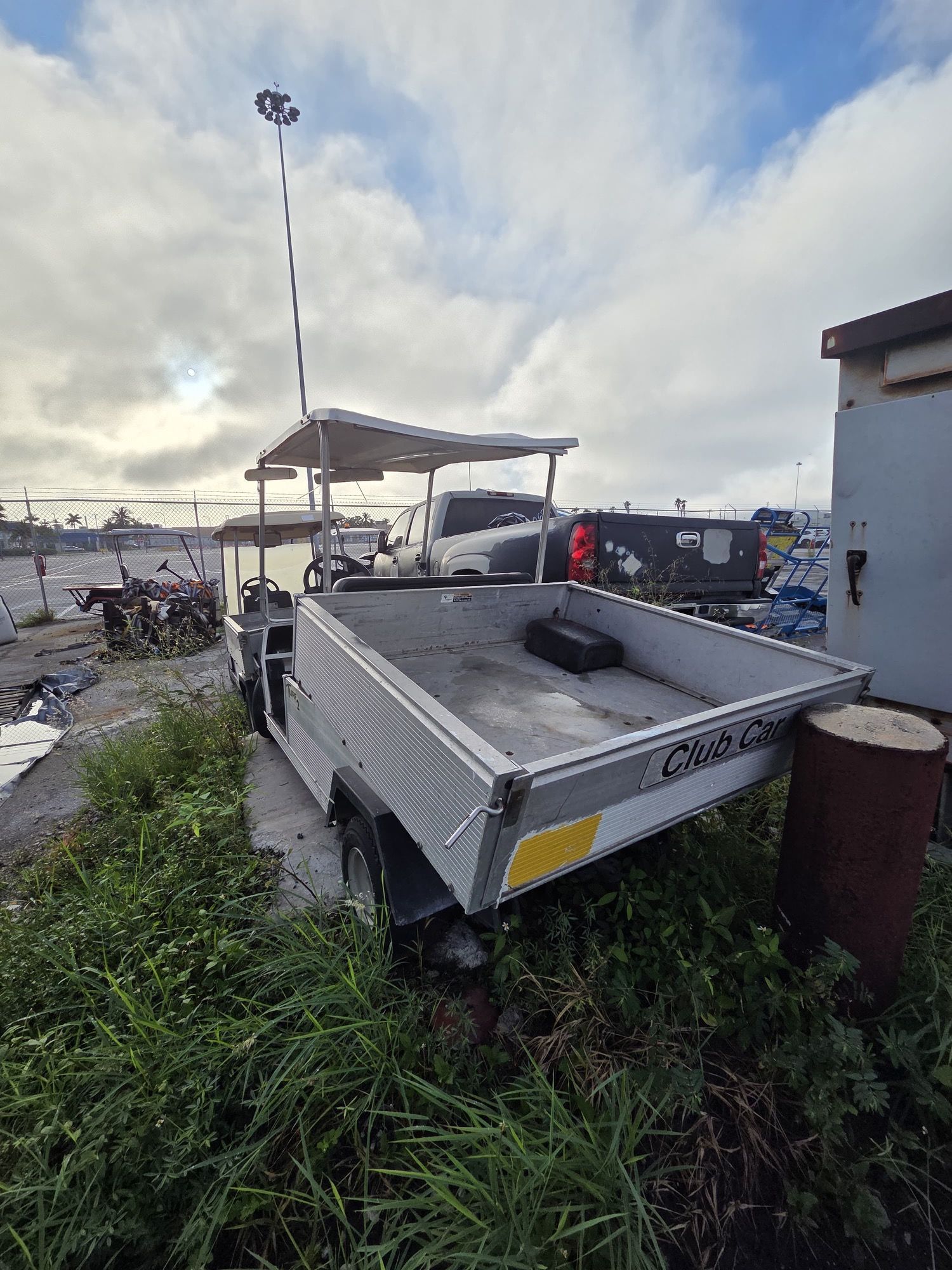 Aluminum utility cart with canopy, outdoors near a building and tall grass.