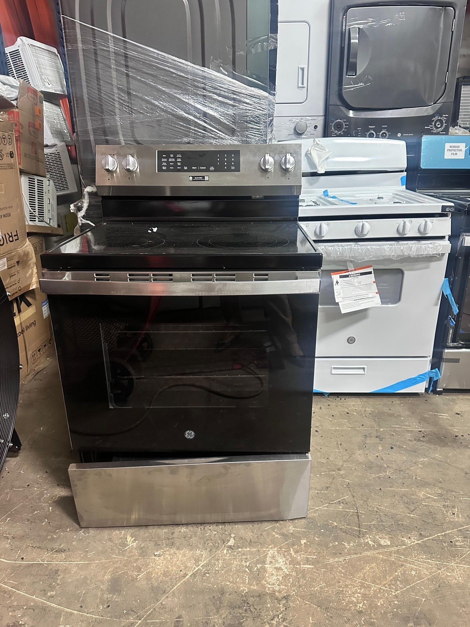 Electric range with stainless steel accents, in a room with other appliances.