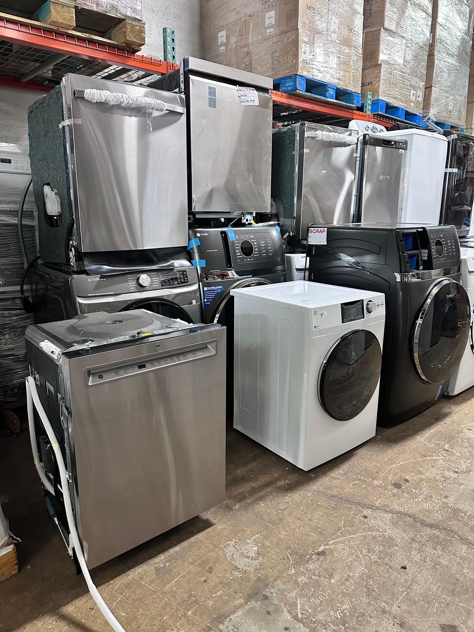 A warehouse display of various stainless steel and white appliances, including dishwashers and washing machines.