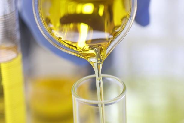 A person is pouring oil into a test tube.