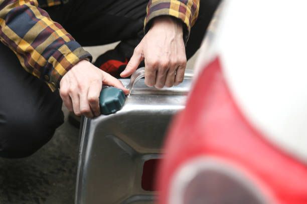 A man in a plaid shirt is kneeling down next to a can of soda.