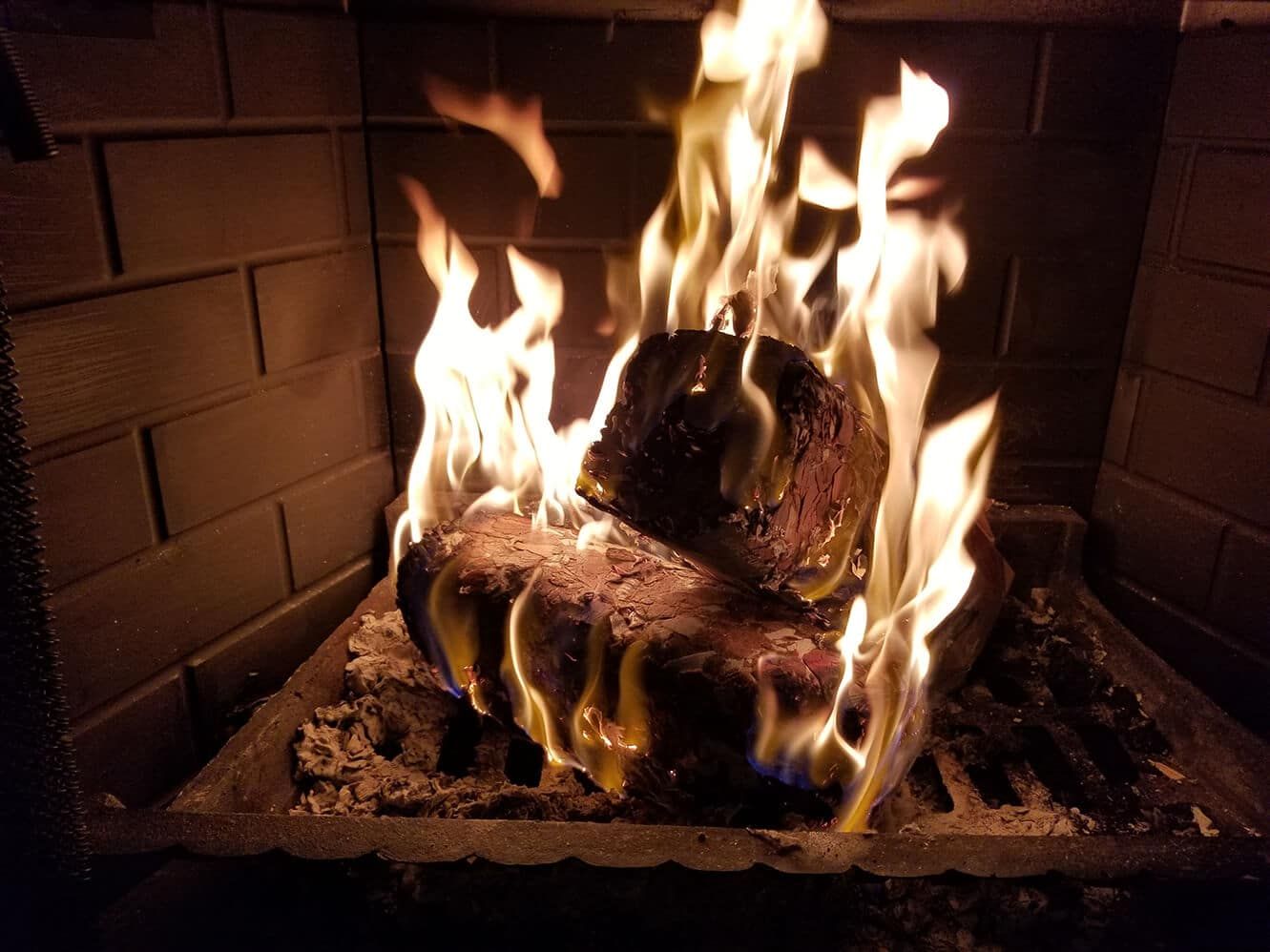 2 stacked EnviroLog firelogs are burning in a brick fireplace, flames engulfing logs.