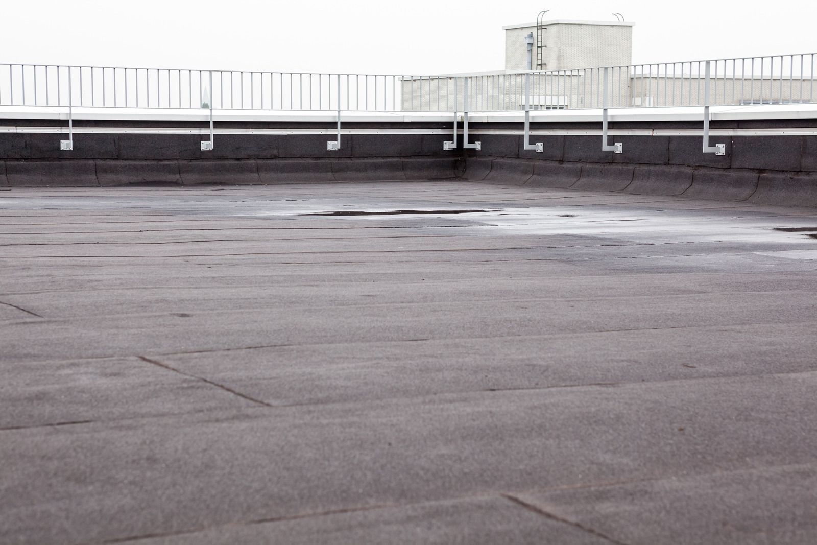 An empty rooftop with a railing and a building in the background