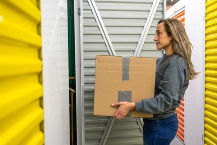 Woman storing box inside storage unit — Daytona, FL — A Place for Your Stuff