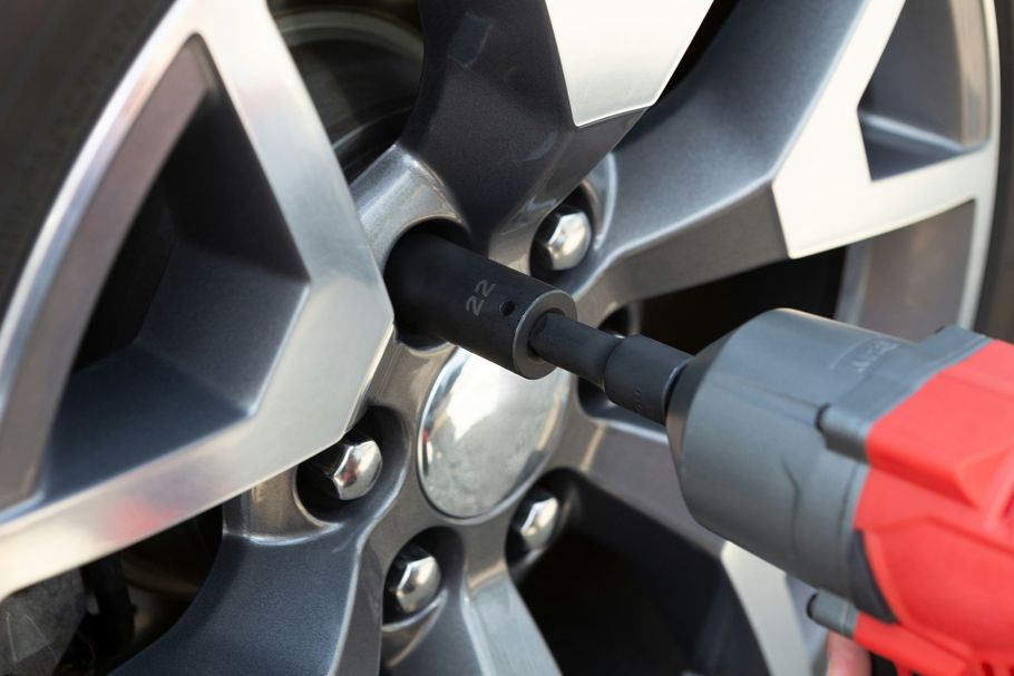 Power drill loosening lug nuts on a car wheel