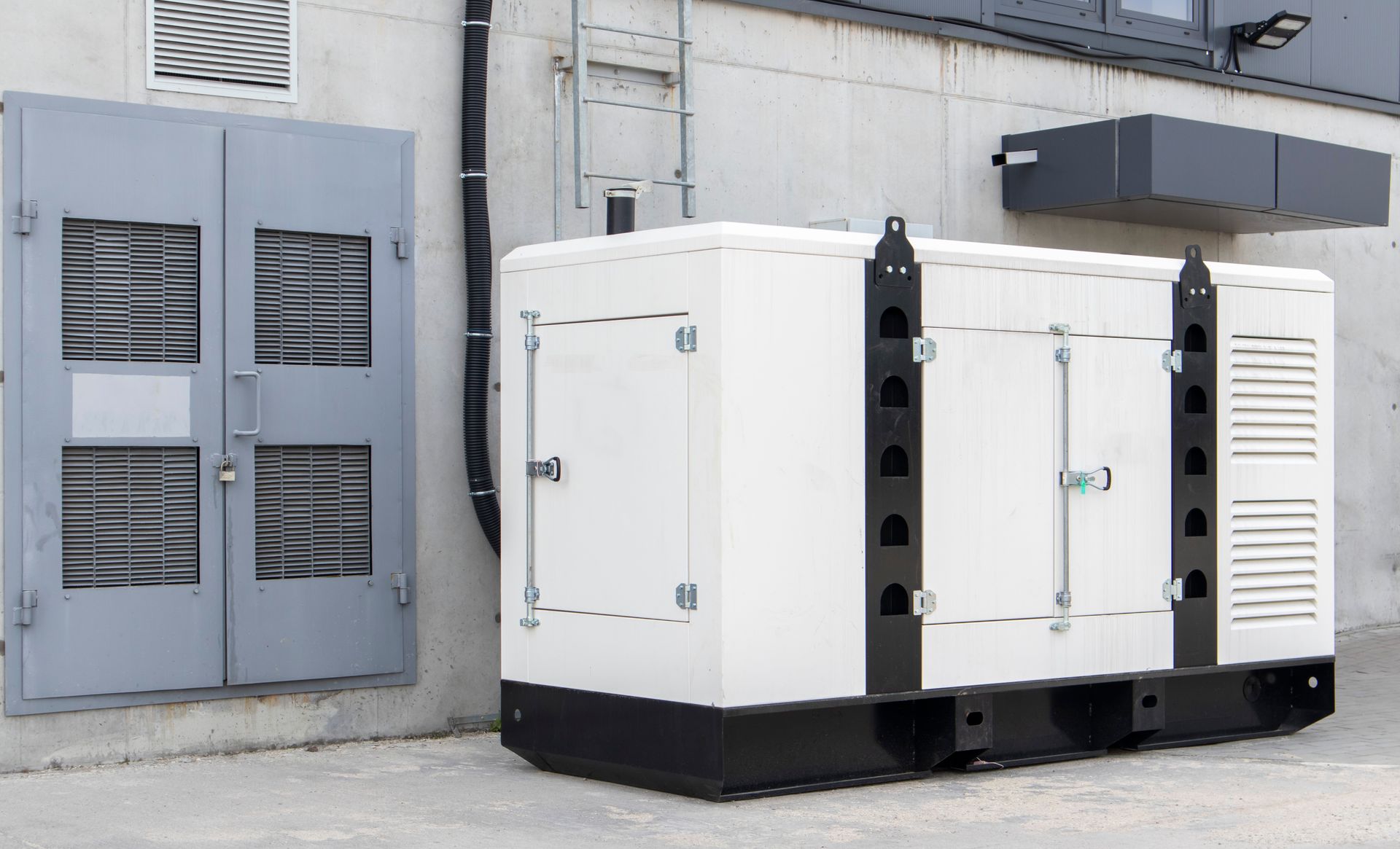 White generator outside building with gray doors.