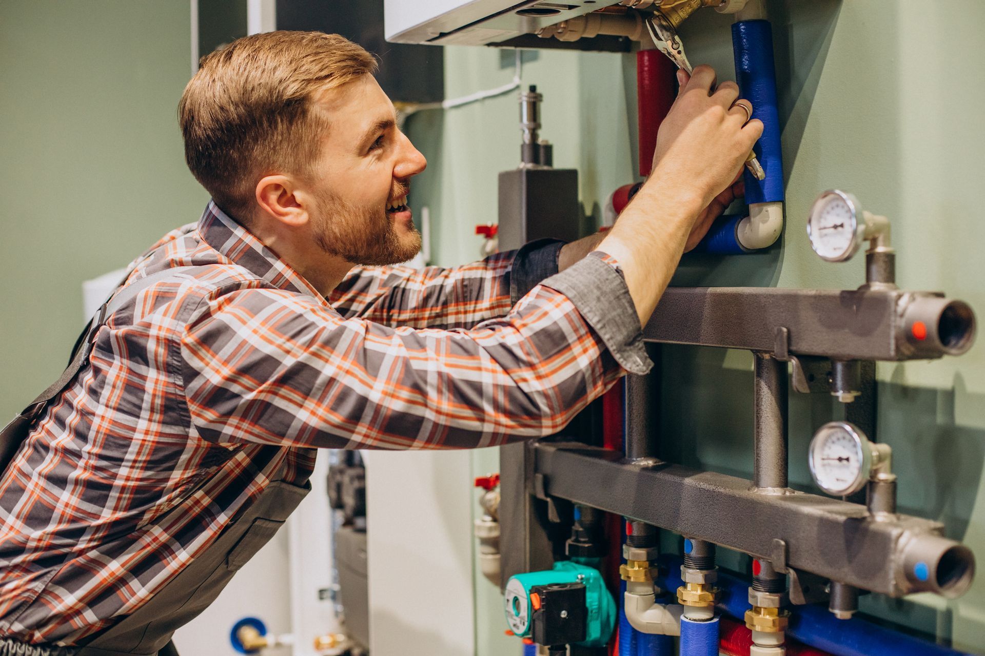 A man is working on a boiler with a wrench.