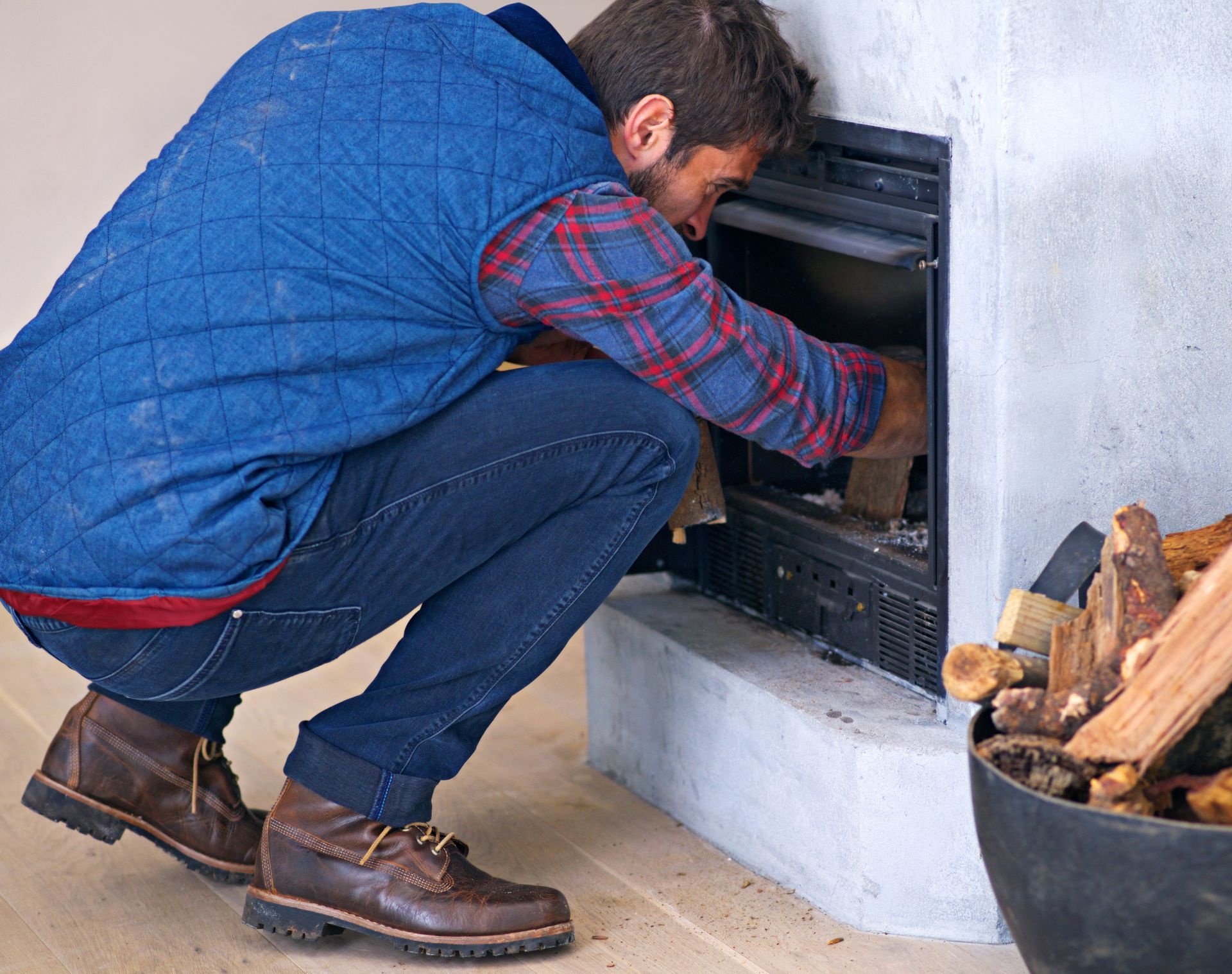 A man is kneeling down in front of a fireplace.