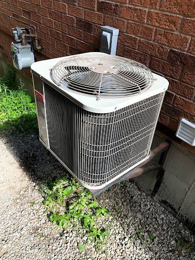 An air conditioner is sitting on the side of a brick building.