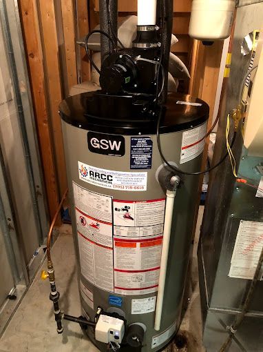A water heater is sitting in a basement next to a furnace.