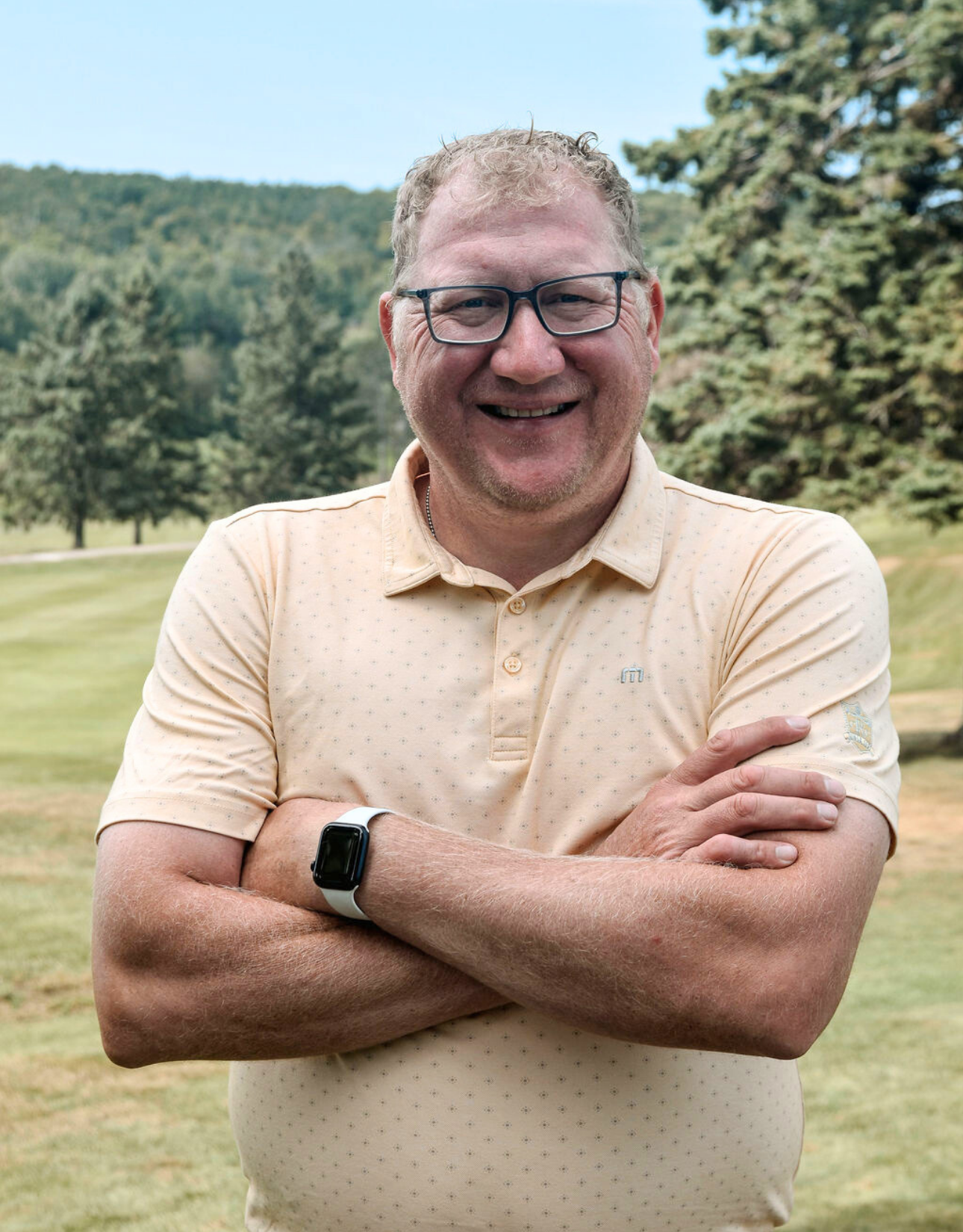A man in a white sweater is smiling for the camera.