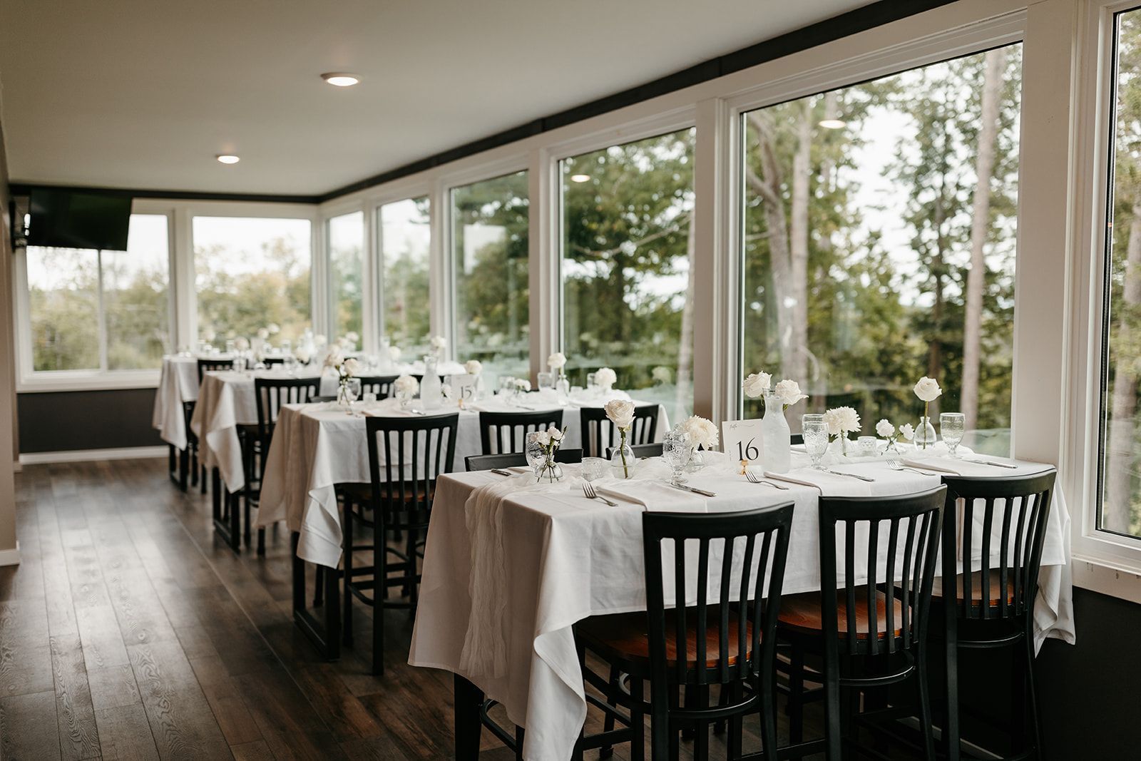 A dining room with tables and chairs and a lot of windows.