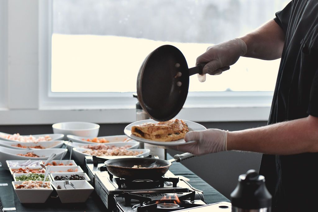 A person is cooking food on a stove in a kitchen.