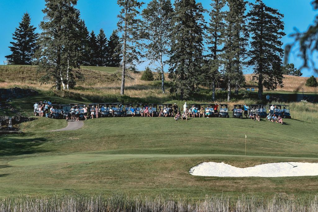 A group of people are standing on top of a golf course.