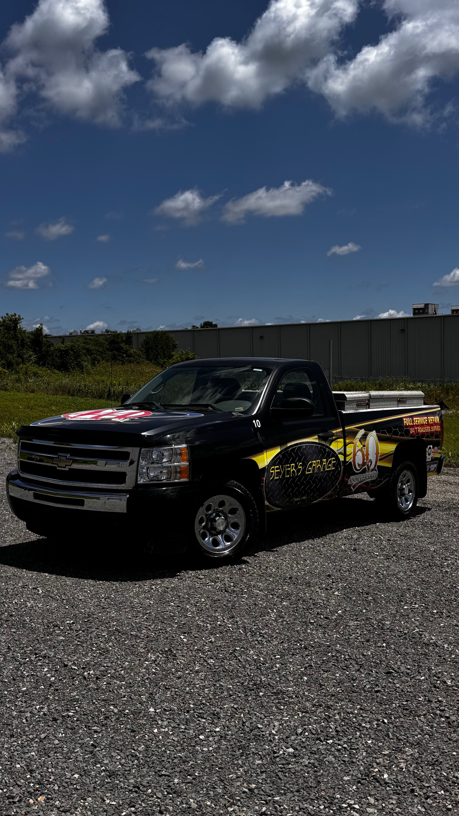 A black truck is parked in a gravel lot on a sunny day. | Seyer Garage