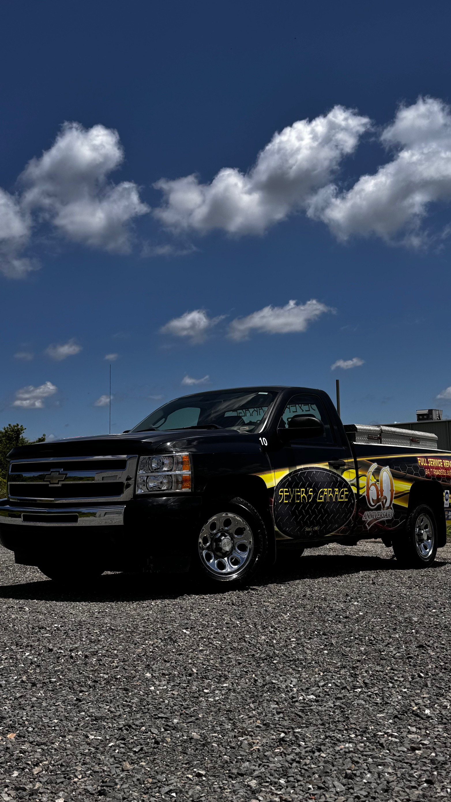 A black and yellow truck is parked in a gravel lot. | Seyer Garage