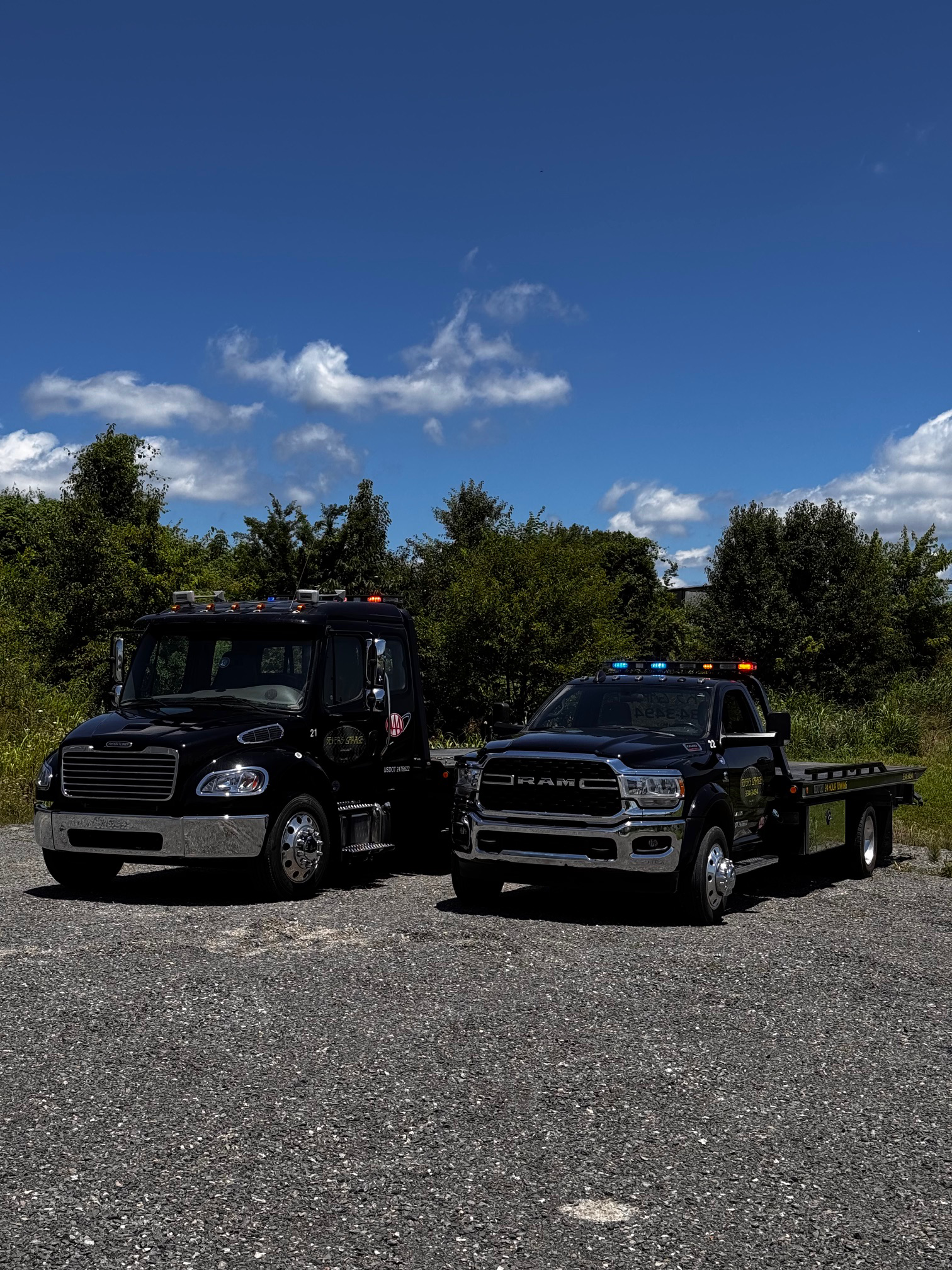 Two tow trucks are parked next to each other in a gravel lot. | Seyer Garage