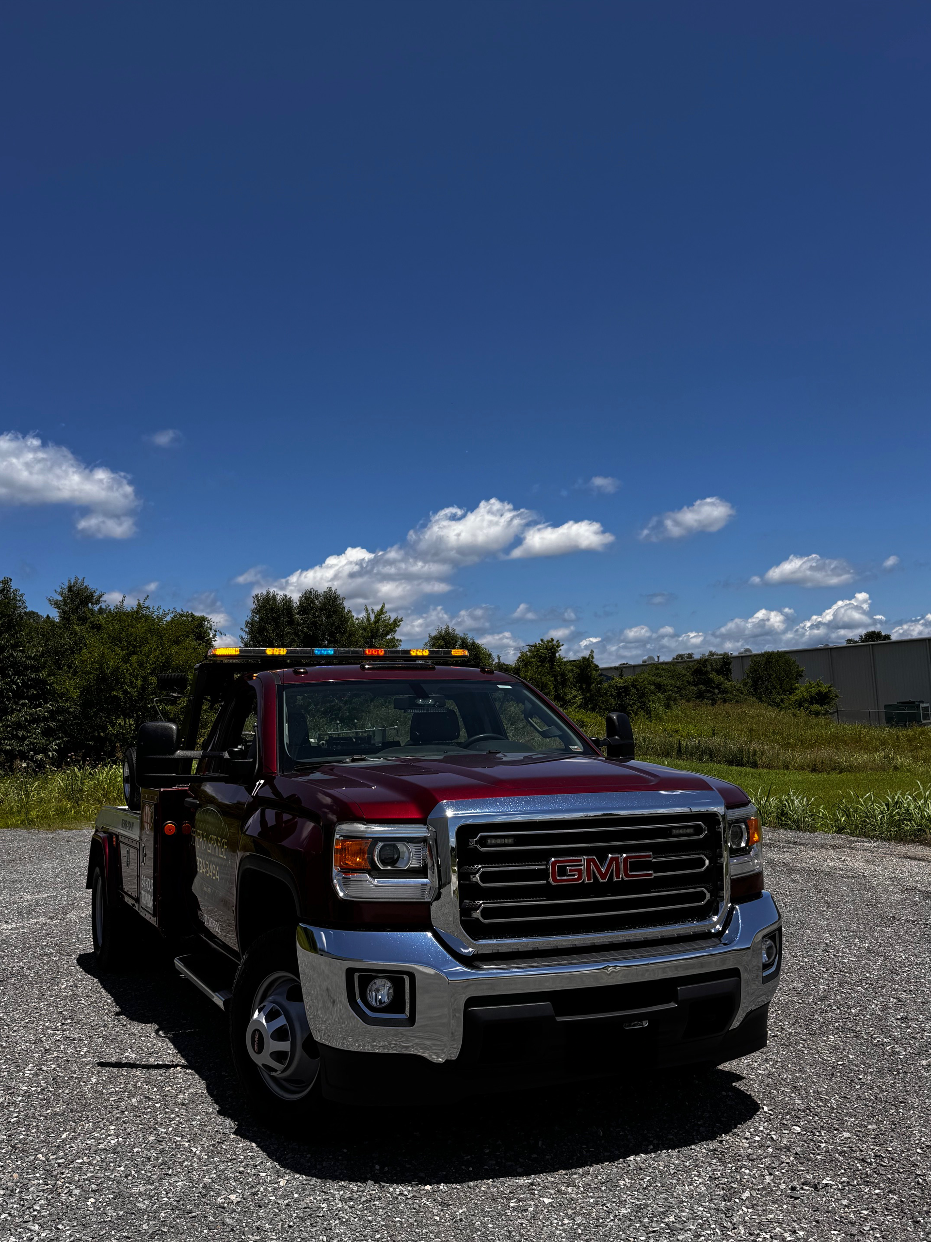 A red gmc truck is parked in a gravel lot on a sunny day. | Seyer Garage