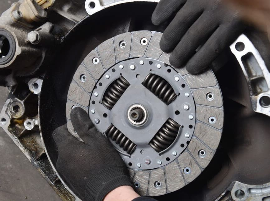 Hands Wearing Black Gloves Installing A Clutch Disc In A Car Engine — MC Automotive Service & Repairs in Maitland, NSW