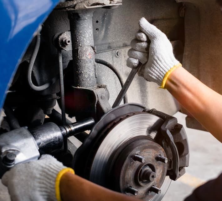 Mechanic Working On A Car's Brakes With A Wrench And An Impact Gun — MC Automotive Service & Repairs in Maitland, NSW