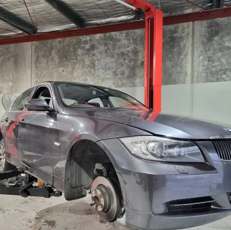 Gray BMW Sedan On A Lift In A Garage, Front Wheel Removed — MC Automotive Service & Repairs in Maitland, NSW