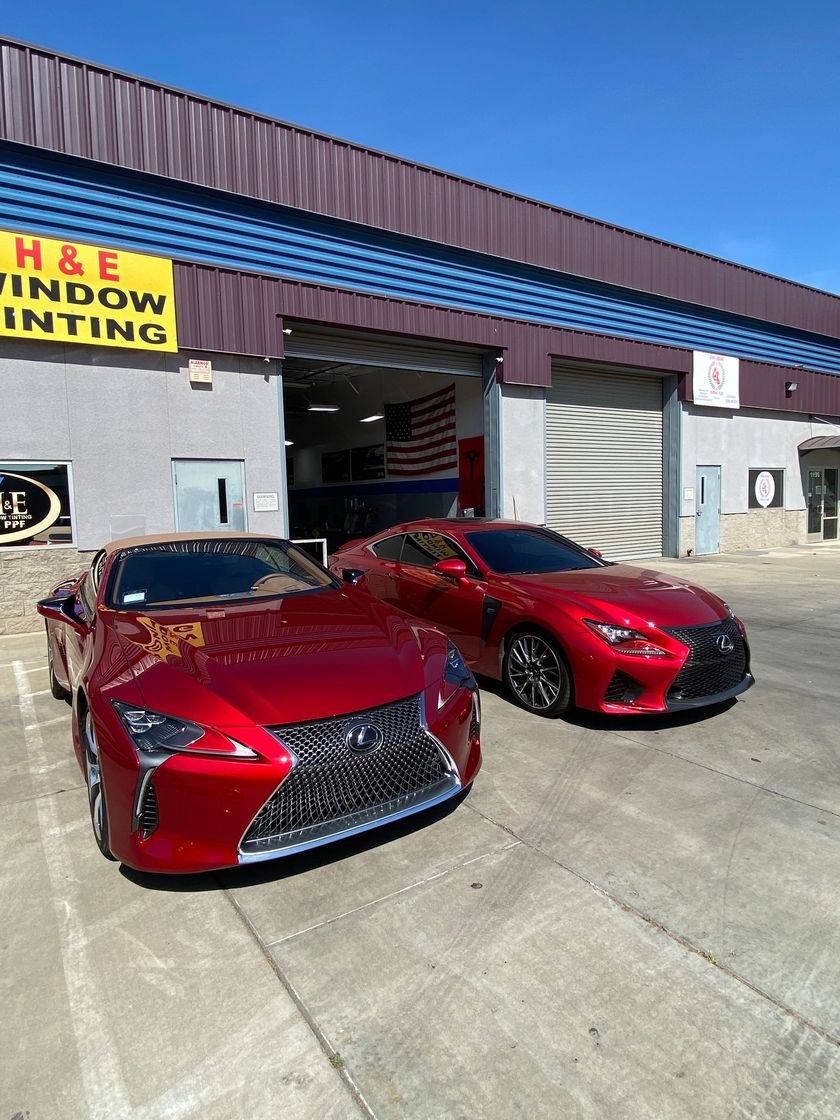 Two red Lexus sports cars parked outside a window tinting shop.