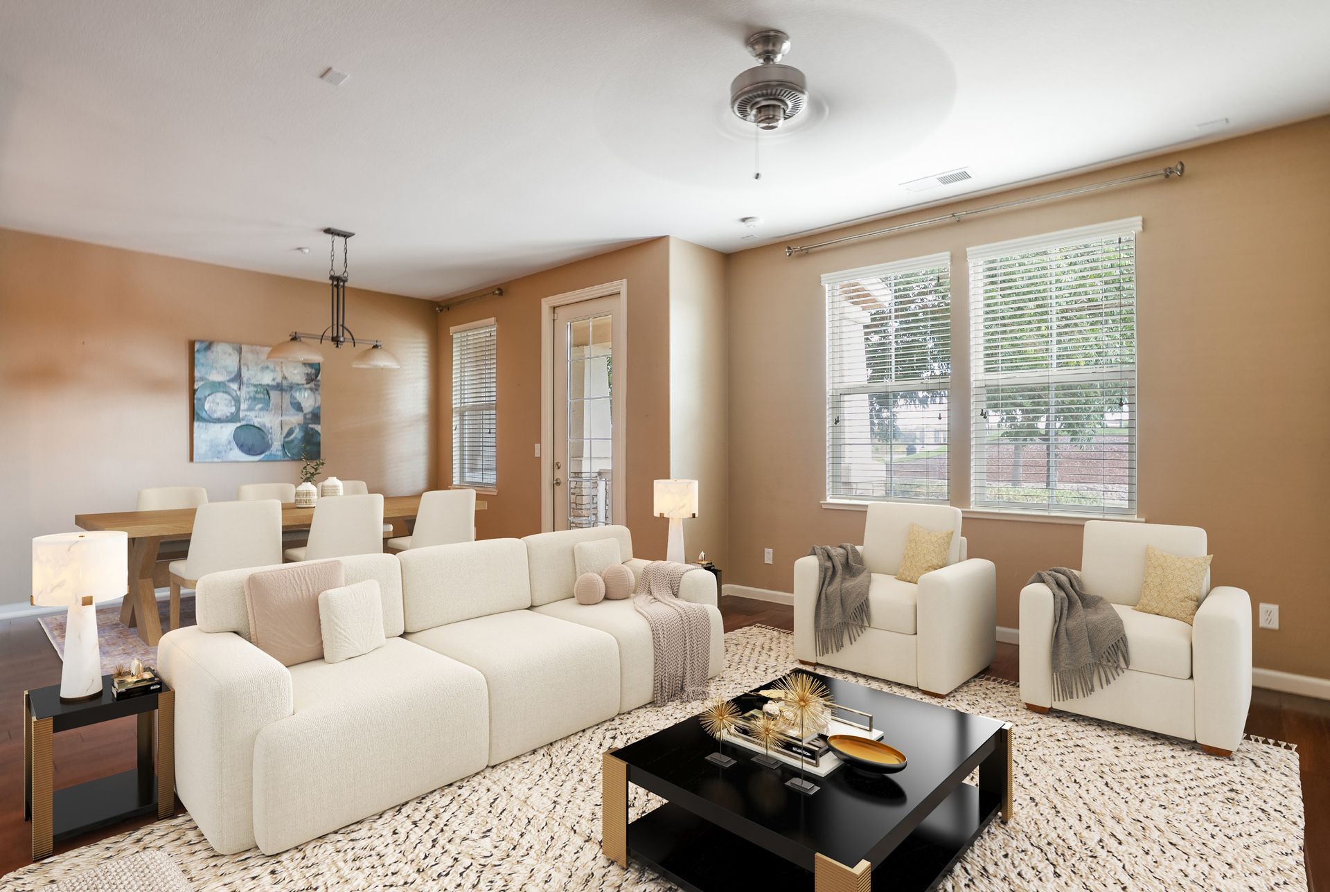 Spacious living room with white furniture, area rug, dining table, and natural light.