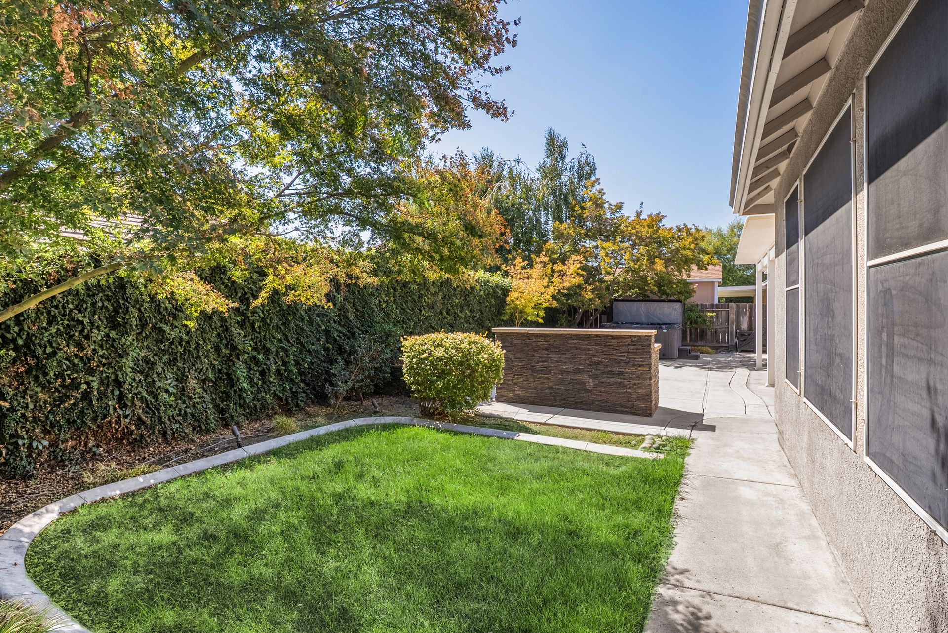 Backyard with green lawn, brick wall, and lush foliage.
